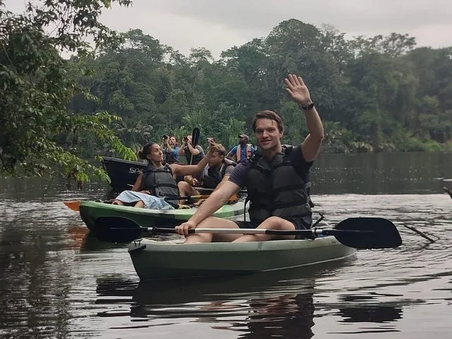 people kayaking on a river surrounded by dense forest