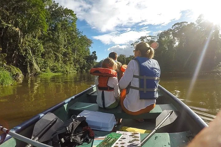 Familie in einem Boot auf einem Fluss, umgeben von üppig grünen Bäumen
